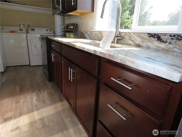 943 Silver King Ave SE, Ocean Shores, WA 98569 - kitchen with washer and dryer, light wood-type flooring, a sink, and light stone counters