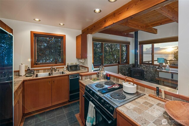 681 Smugglers Cove Rd, Friday Harbor, WA 98250 - kitchen with a sink, tile counters, a wood stove, brown cabinetry, and black appliances