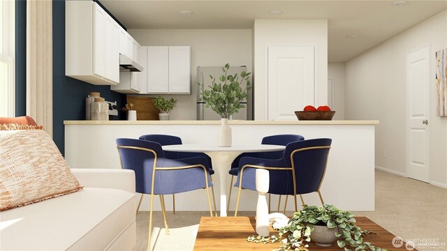 kitchen featuring a peninsula, carpet, under cabinet range hood, white cabinetry, and a breakfast bar area