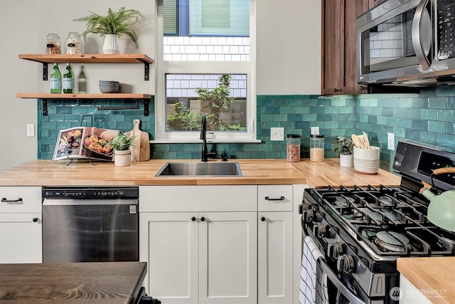 kitchen with decorative backsplash, wood counters, a sink, and stainless steel appliances