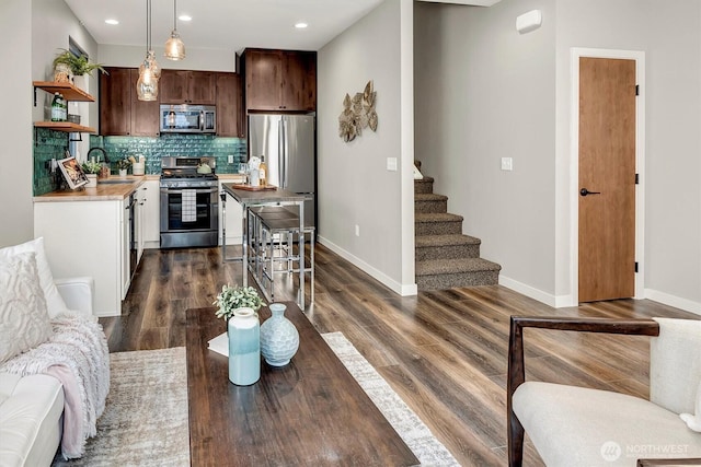 kitchen featuring light countertops, tasteful backsplash, dark wood-type flooring, appliances with stainless steel finishes, and open shelves