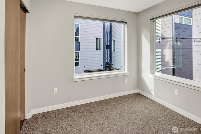carpeted spare room featuring baseboards and a healthy amount of sunlight