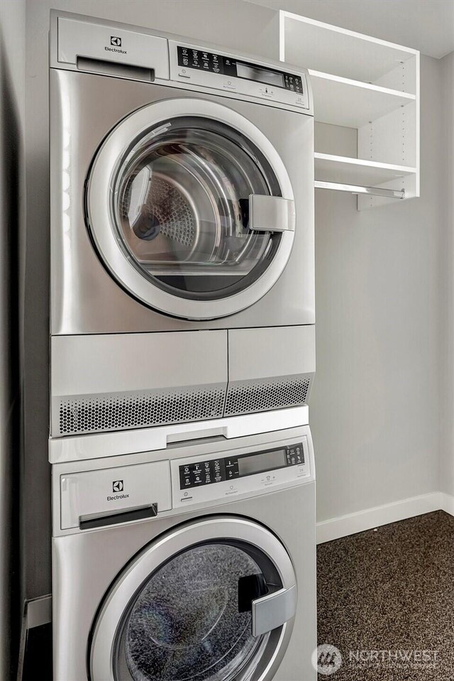 washroom with stacked washer / dryer, baseboards, and laundry area