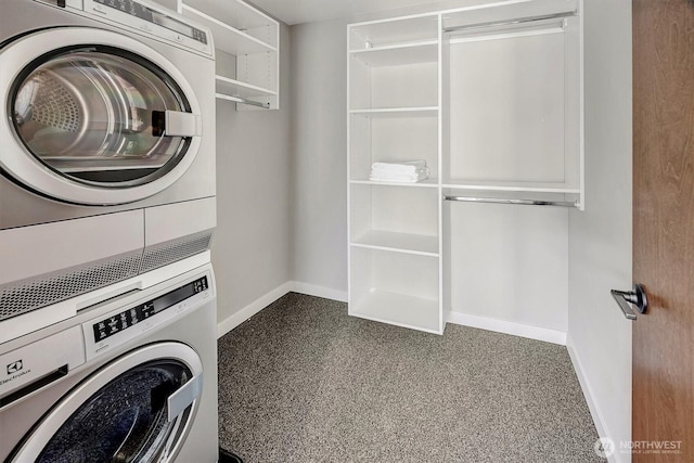 washroom featuring baseboards, stacked washer / drying machine, and laundry area
