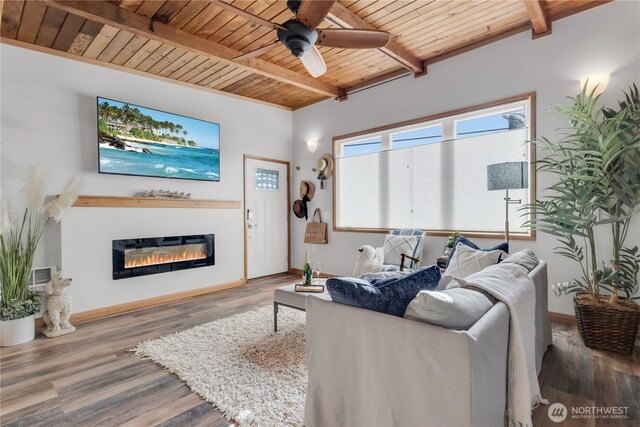 living room with beamed ceiling, ceiling fan, a glass covered fireplace, and wood ceiling