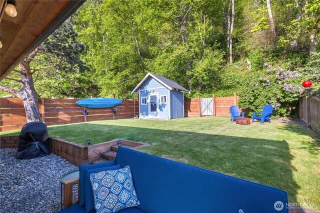 view of yard with a fenced backyard, a shed, and an outbuilding