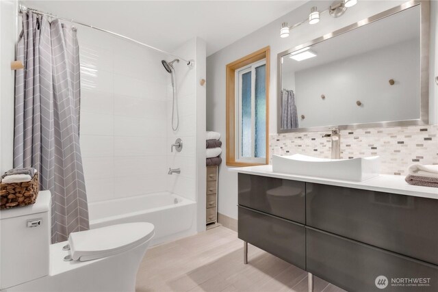 full bathroom featuring vanity, shower / tub combo with curtain, toilet, and tasteful backsplash