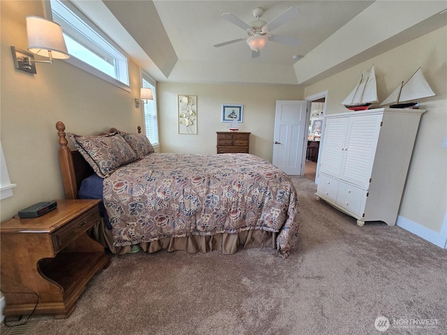 carpeted bedroom with a ceiling fan and a tray ceiling