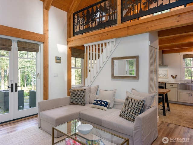 living area featuring high vaulted ceiling, beam ceiling, stairway, french doors, and wood finished floors