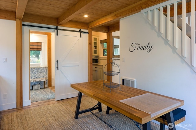 office space with beam ceiling, wood ceiling, a barn door, light wood-type flooring, and visible vents