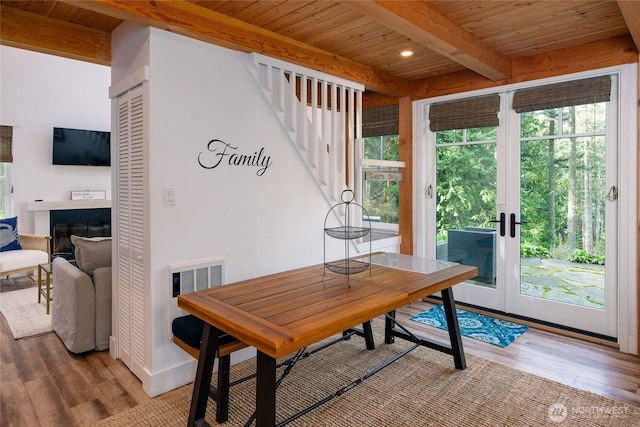 dining space featuring light wood-type flooring, wooden ceiling, and beam ceiling