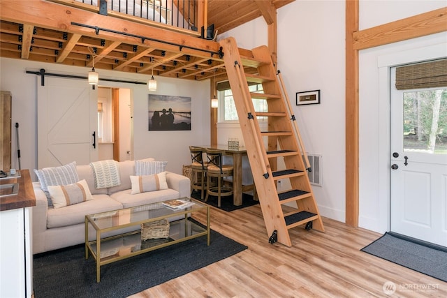 living area with baseboards, a barn door, and light wood-style floors