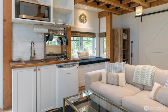 kitchen with open floor plan, white cabinetry, stainless steel appliances, backsplash, and a sink