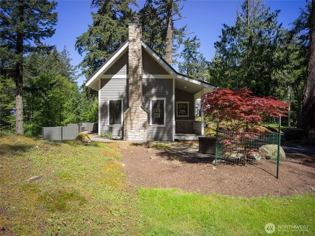 rear view of house featuring a chimney and fence