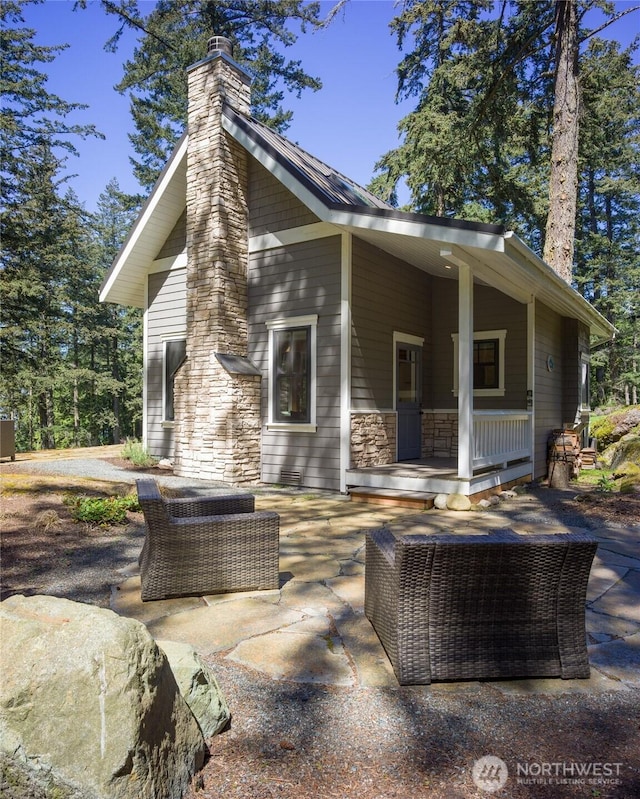 exterior space with a chimney, covered porch, and a patio area