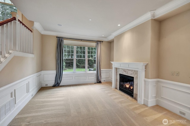 unfurnished living room featuring light colored carpet, a decorative wall, and ornamental molding