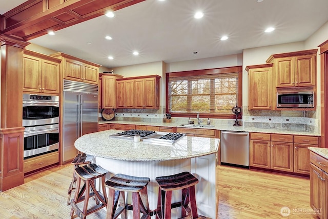 kitchen with decorative backsplash, a kitchen breakfast bar, a sink, and appliances with stainless steel finishes