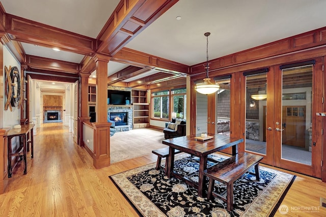 dining room with french doors, a fireplace, light wood-style floors, and ornamental molding