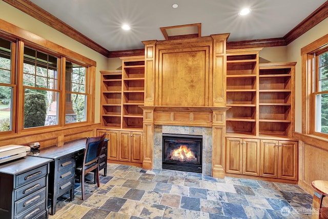home office with stone finish flooring, a wealth of natural light, crown molding, and a high end fireplace