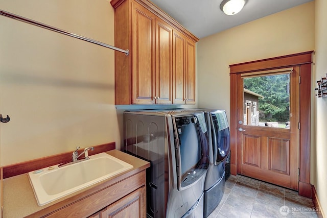clothes washing area with cabinet space, washer and clothes dryer, and a sink