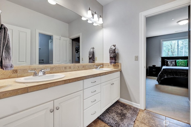 ensuite bathroom with baseboards, a sink, double vanity, and ensuite bathroom