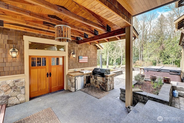 view of patio with a grill, a hot tub, and an outdoor kitchen