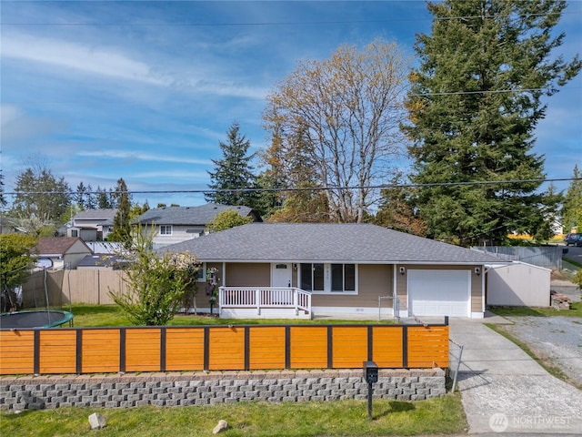 ranch-style home with a fenced front yard, driveway, covered porch, roof with shingles, and a garage