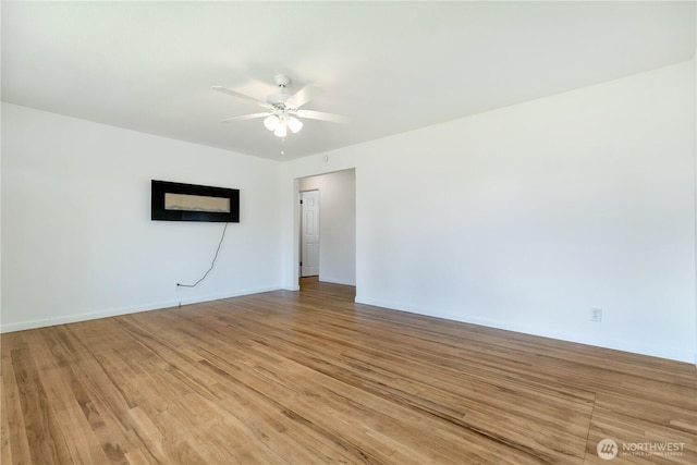 spare room featuring light wood-style flooring, baseboards, and ceiling fan