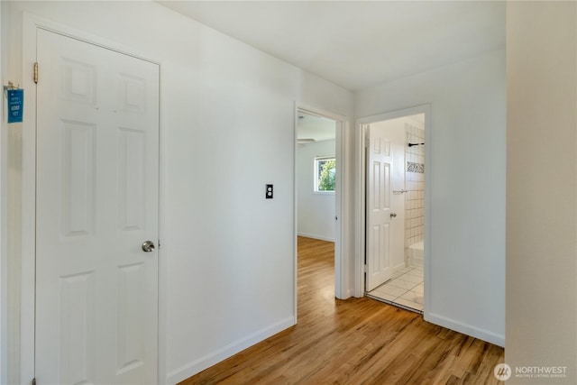hall with baseboards and light wood-type flooring