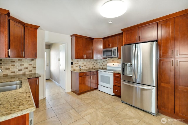 kitchen featuring light stone countertops, stainless steel appliances, a sink, and tasteful backsplash