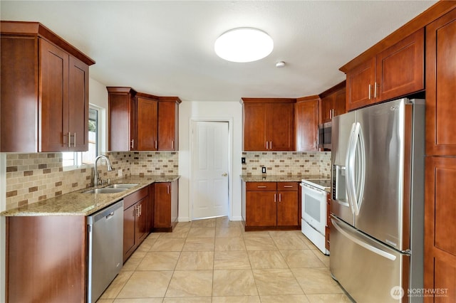 kitchen with light stone counters, a sink, brown cabinetry, decorative backsplash, and stainless steel appliances
