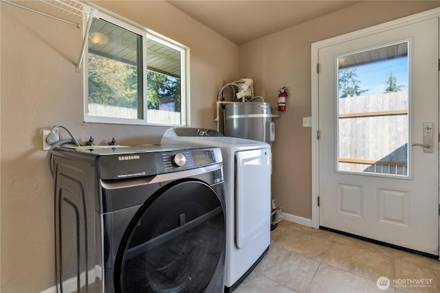 laundry room featuring washing machine and dryer, strapped water heater, laundry area, and light tile patterned flooring