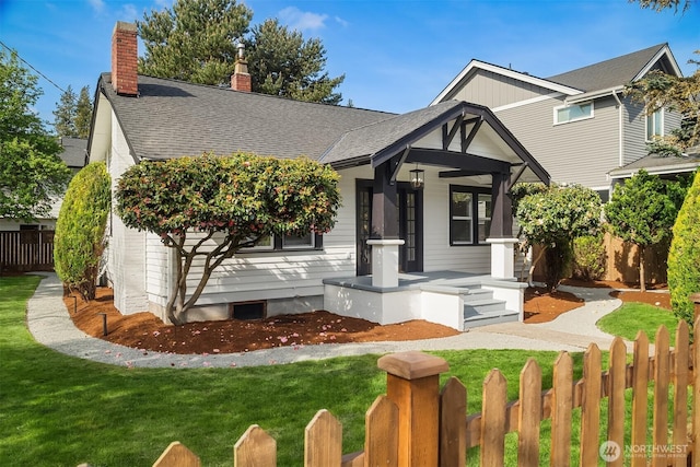 view of front of property with a chimney, fence private yard, roof with shingles, and a front lawn