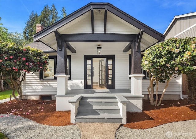 property entrance featuring a porch, a chimney, and a shingled roof