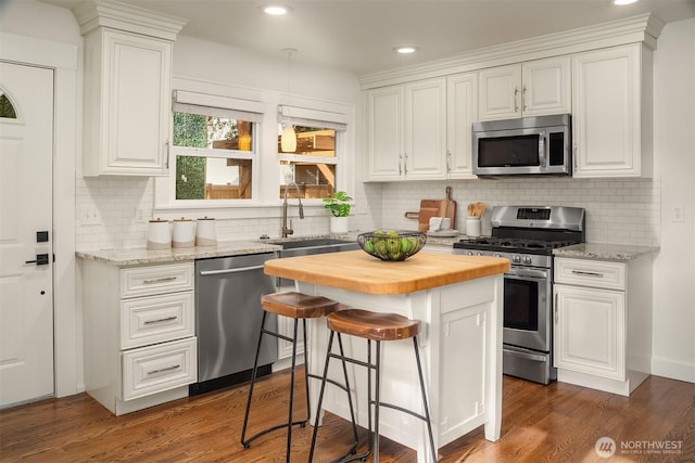kitchen featuring wooden counters, dark wood-type flooring, white cabinets, a sink, and stainless steel appliances
