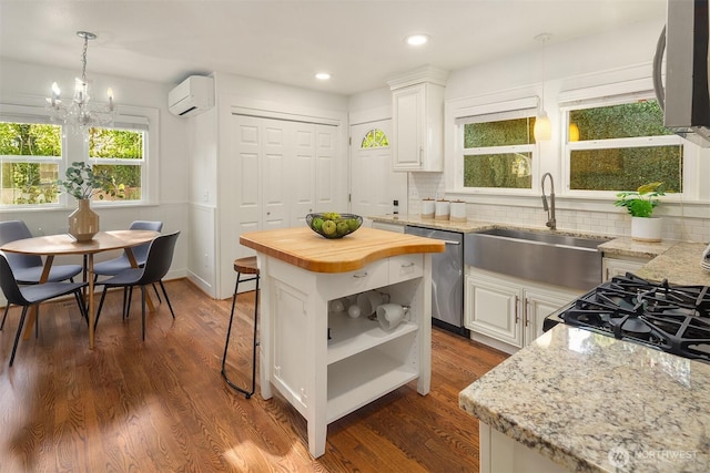 kitchen featuring plenty of natural light, a wall mounted air conditioner, dishwasher, a sink, and wood counters