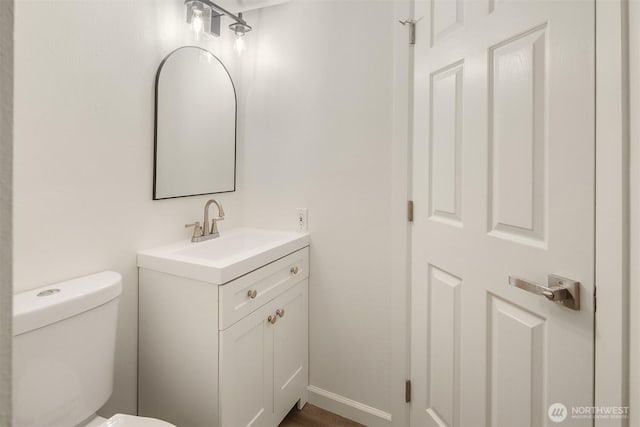 half bath with vanity, baseboards, and toilet