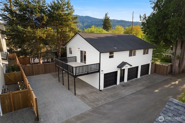 view of front of home featuring driveway, fence, a mountain view, an attached garage, and a shingled roof