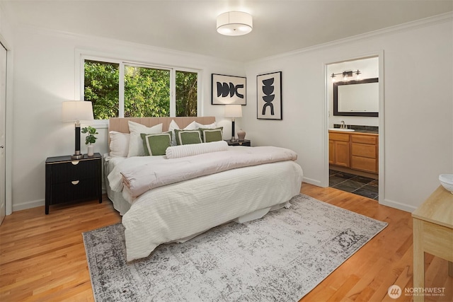 bedroom with crown molding, a sink, ensuite bath, baseboards, and light wood-type flooring