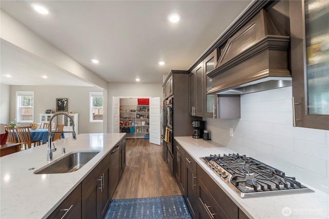 26334 203rd Pl SE, Covington, WA 98042 - kitchen featuring appliances with stainless steel finishes, wall chimney exhaust hood, dark brown cabinetry, glass insert cabinets, and light stone countertops
