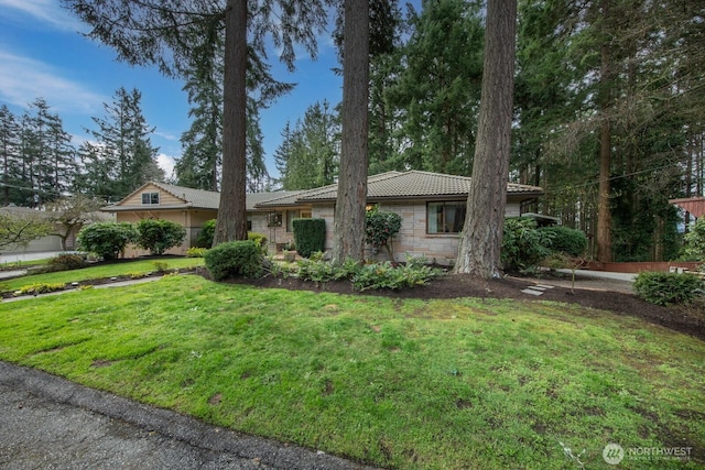 single story home with a tiled roof, a front lawn, and stone siding