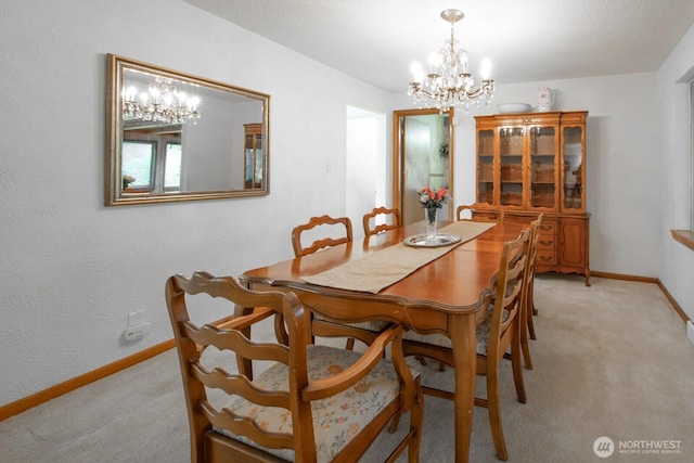 dining area featuring a chandelier, light colored carpet, and baseboards