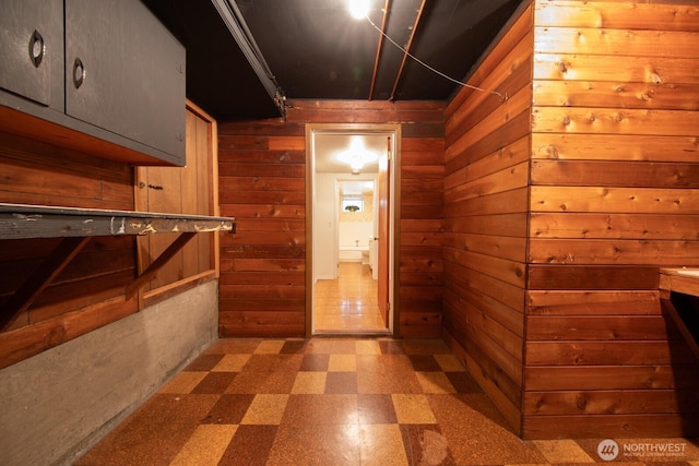 hallway with tile patterned floors and wood walls