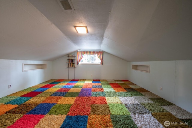 additional living space with visible vents, carpet flooring, and lofted ceiling