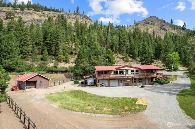 exterior space with an outbuilding, driveway, a mountain view, and fence