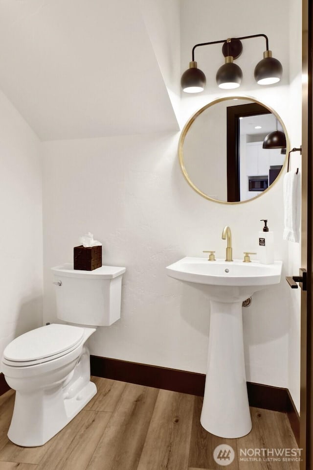 half bathroom with toilet, baseboards, and wood finished floors
