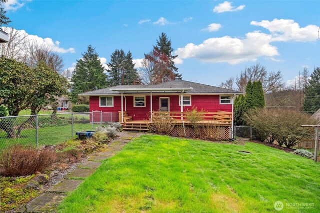 rear view of property featuring a fenced backyard and a lawn