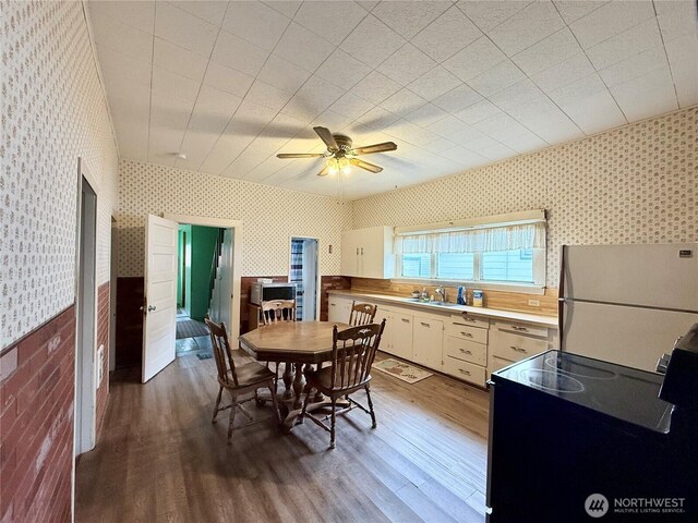 21 Cummings Ave, Elma, WA 98541 - dining space with a ceiling fan, wallpapered walls, a wainscoted wall, and wood finished floors