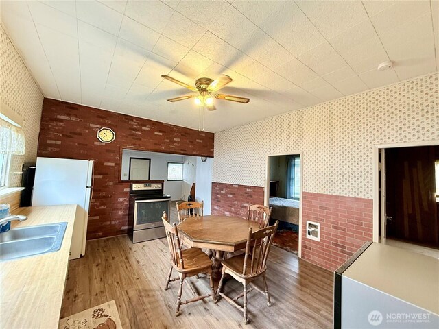 21 Cummings Ave, Elma, WA 98541 - dining area featuring wallpapered walls, light wood-style flooring, ceiling fan, and brick wall