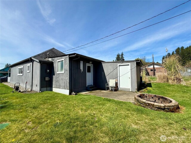 21 Cummings Ave, Elma, WA 98541 - back of property with a lawn, an outbuilding, an outdoor fire pit, and a patio area